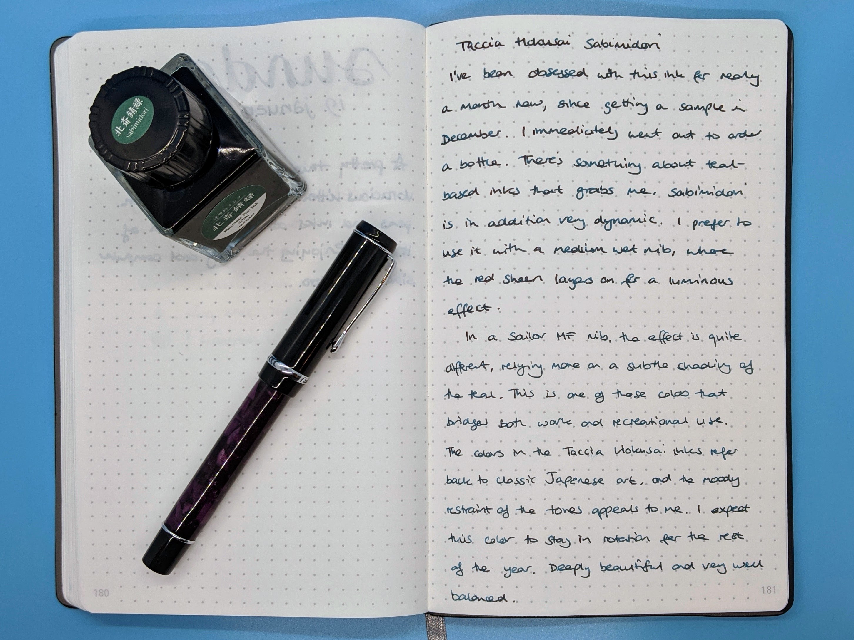 Writing sample on a notebook, with a bottle of ink.